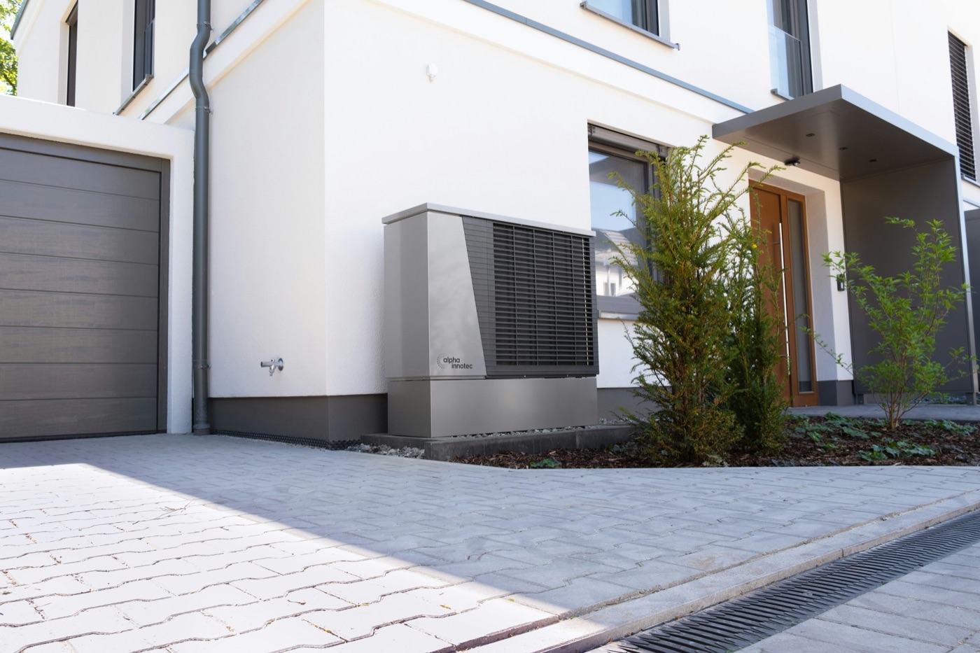 Pompe à chaleur air-eau posée sur socle devant une maison